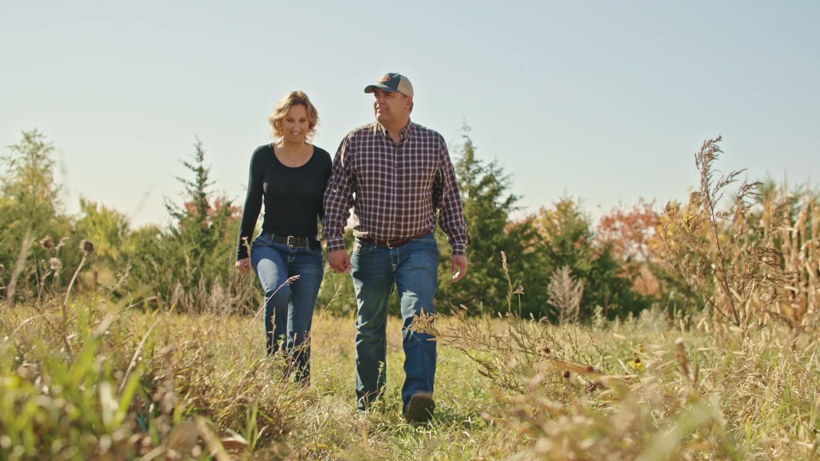 Taylor and Cassandra Sumption of Anthem Oats walking their field